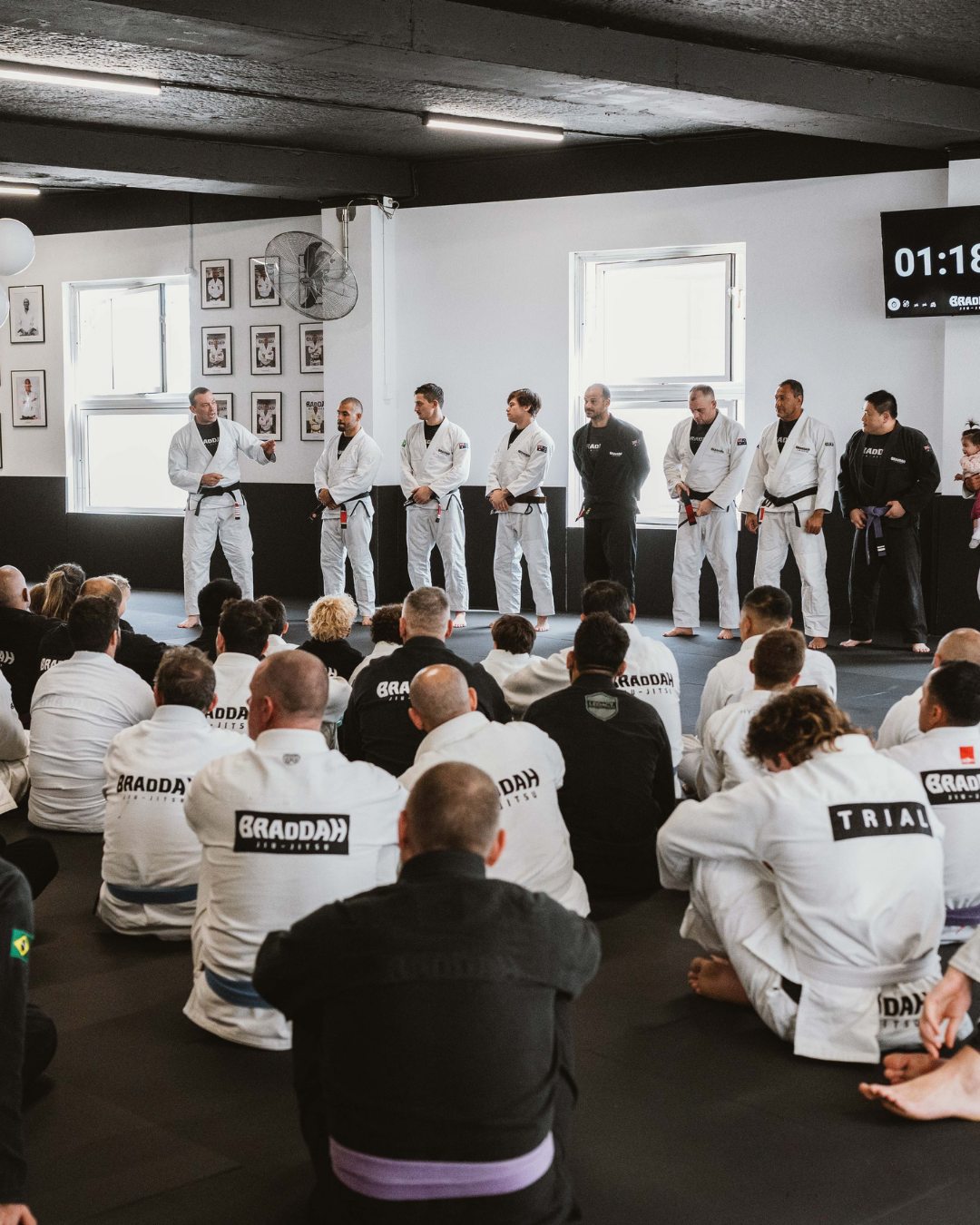 Braddah Jiu Jitsu students gathered on the mat as instructors demonstrate Brazilian Jiu-Jitsu techniques during a training session.