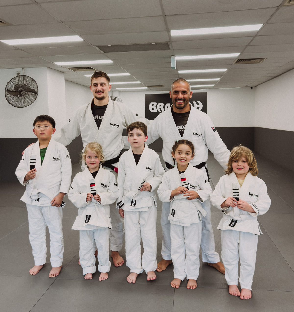 Braddah Jiu-Jitsu instructors posing with children from the kids program